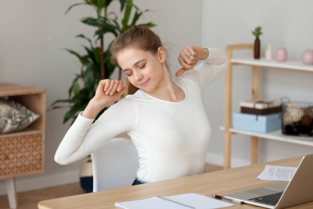 istock Satisfied young woman stretching, doing exercise at workplace 1143696587