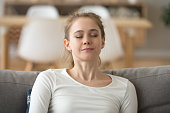 Close up calm peaceful woman relaxing with closed eyes on sofa