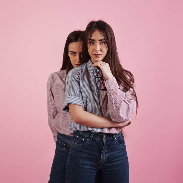 istock Stands in the studio with pink background. Second girl behind her sister 1143697942