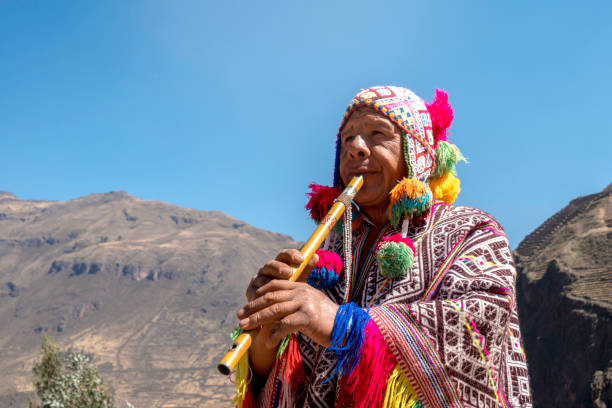 Senior man dressing traditional peruvian clothing and playing flute