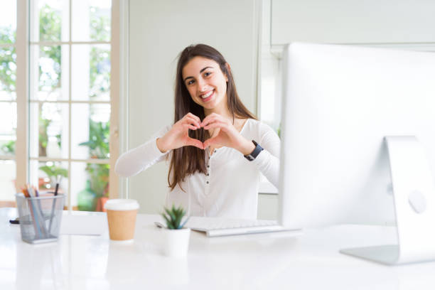 istock Beautiful young woman working using computer smiling in love showing heart symbol and shape with hands. Romantic concept. 1143703272