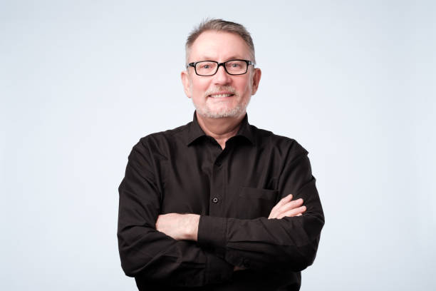 istock Confident mature man looking at camera and smiling while keeping arms crossed 1143704108