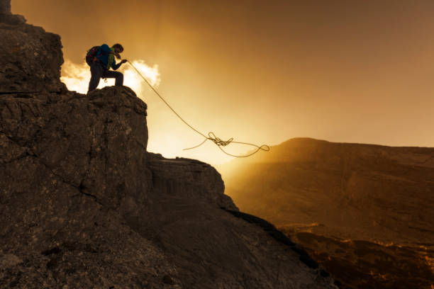 grimpeur de roche jette sa corde dans le coucher du soleil - mountain climbing rock climbing motivation awe photos et images de collection