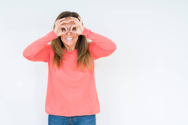 istock Beautiful middle age woman over isolated background doing ok gesture like binoculars sticking tongue out, eyes looking through fingers. Crazy expression. 1143706770