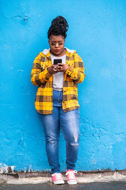istock Afro woman using smart phone on a blue background 1143707423