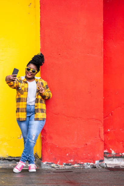 istock Smiling afro woman on colorful background taking selfie 1143707428