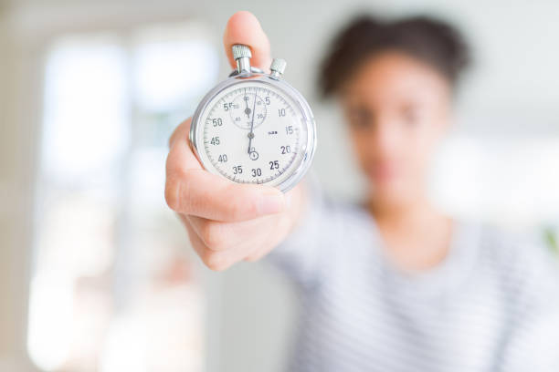 istock Young african american woman holding stopwatch with a confident expression on smart face thinking serious 1143708983