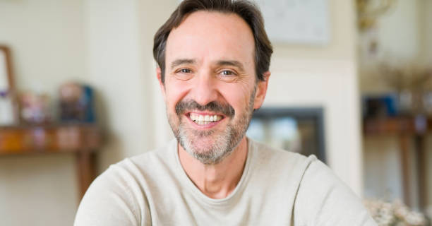 istock Handsome middle age man sitting on the floor smiling at the camera at home 1143709121