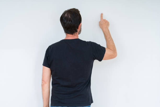 istock Senior man over isolated background Posing backwards pointing behind with finger hand 1143709159