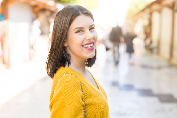 beautiful young woman smiling cheerful walking by the shops on the street on a sunny days, casual pretty girl shopping at the town - comerce imagens e fotografias de stock