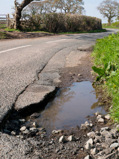 istock Unrepaired pothole - surface damage to tarmac on a rural road 1143710625