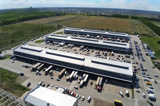 Aerial drone view of group of large modern industrial warehouse or factory buildings in suburban city area.Logistic transportation cargo terminal.