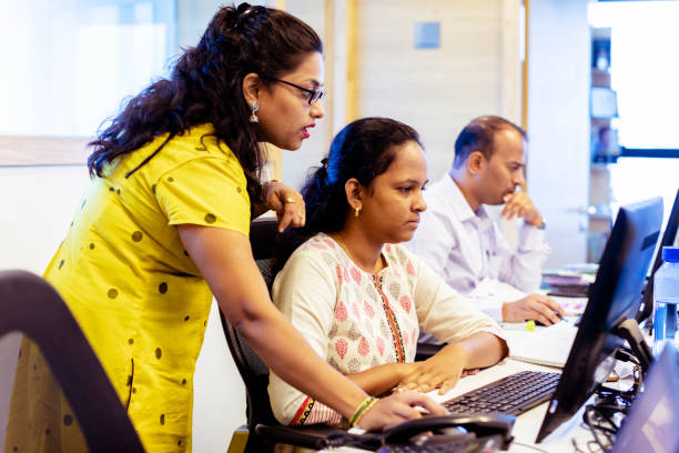 Female Office Manager Training New Staff about their CRM System Corporate Business, Indian, Office - Female Business Executive Training One to One using a Desktop Computer india train stock pictures, royalty-free photos & images
