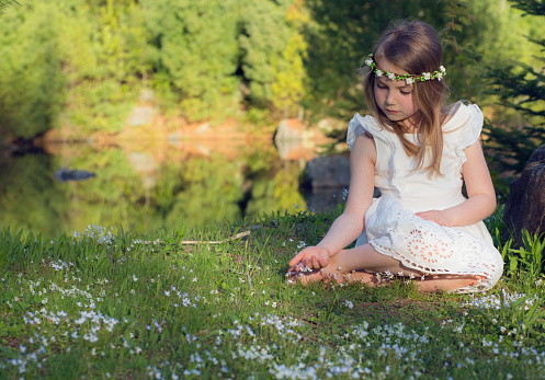 Portrait of a 6 year old girl wearing a white dress and flower headband on a summer day