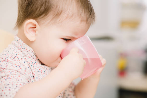 the child in the kitchen drinks water