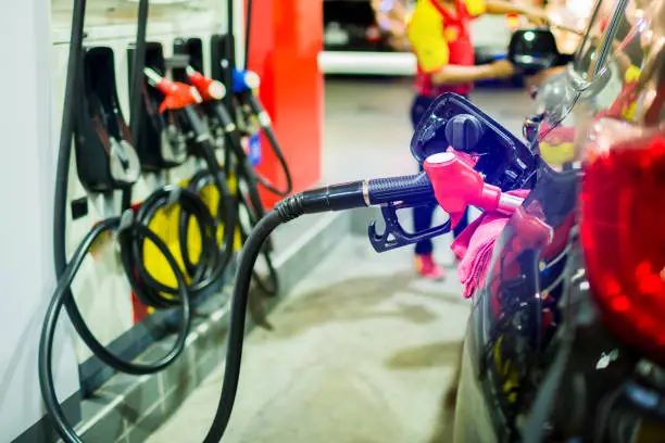 Photo of refilling the car with fuel at the gas  station and blurry staff background, black car in gas station