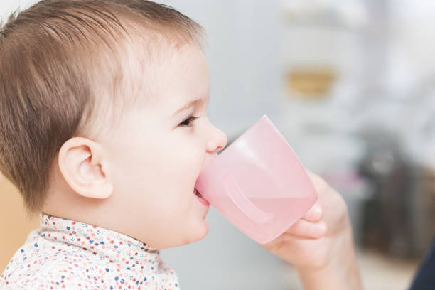 istock child in the kitchen drinking from a cup of water 1143723199