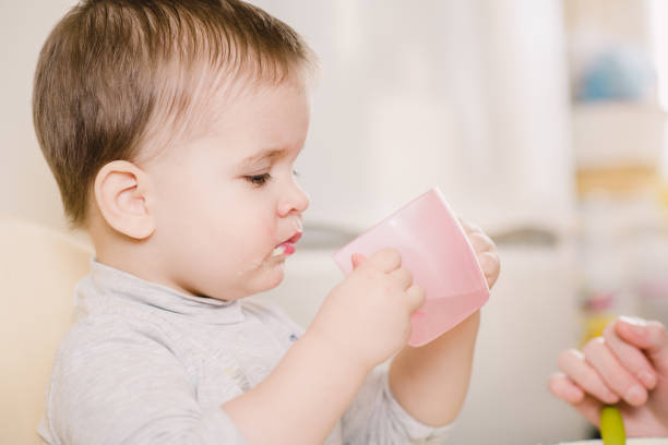 istock child in the kitchen drinking from a cup of water 1143723243
