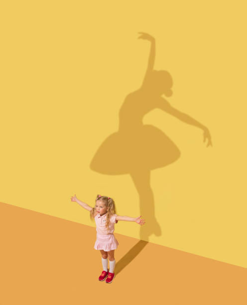 Dream about ballet Get the best role in life. Childhood and dream concept. Conceptual image with child and shadow on the yellow studio wall. Little girl want to become ballerina, ballet dancer, artist in theatre. ballerina shadow stock pictures, royalty-free photos & images