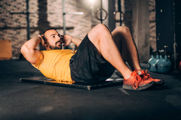 istock Young muscular athlete doing a sit ups workout in a gym gym 1143723623