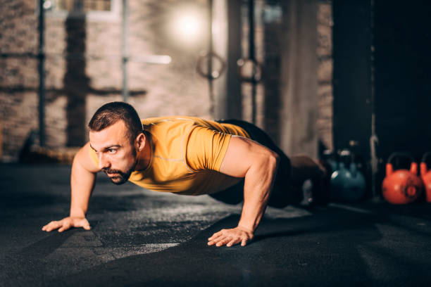 istock Young male athlete doing push ups workout in a gym gym 1143725098