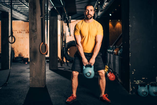 istock Active young muscular athlete doing a kettlebell squatting workout in a gym gym 1143726986