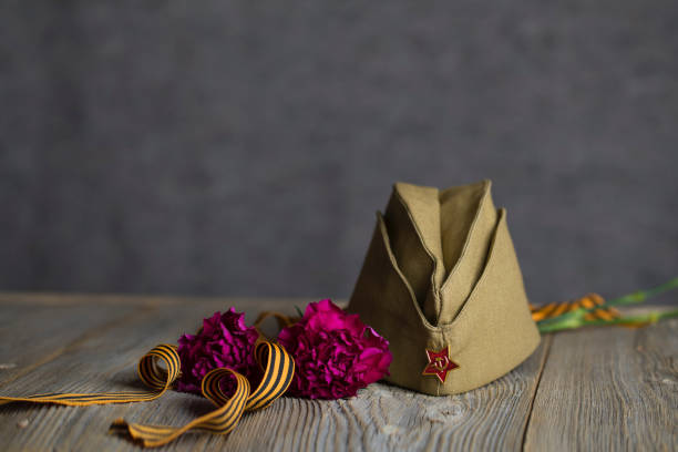 istock Military cap, carnations, Saint George ribbon on a wooden surface. 1143728602