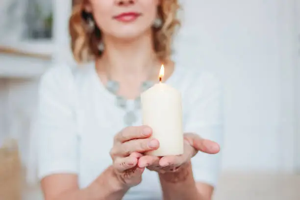 Photo of Blonde young woman in white clothing with mehendi holding burning candle