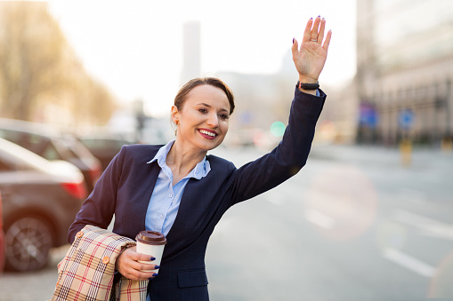 Woman waving for taxi on city street