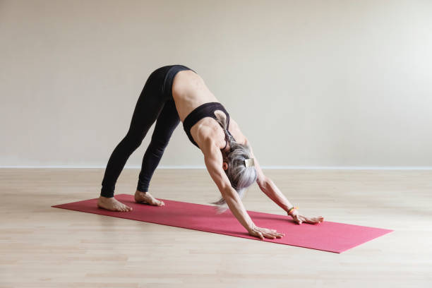 Master Yoga woman doing downdog. Adho Mukha Svanasana. Adult woman wearing gray sportswear working out in indoor. Fit yogi woman doing Downward-facing dog pose. Adho Mukha Svanasana. downward facing dog position stock pictures, royalty-free photos & images