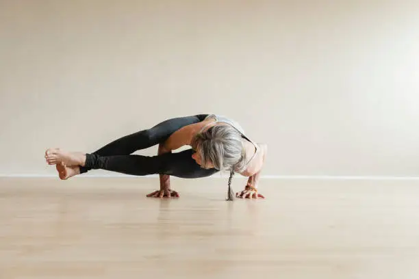 Photo of Master Yoga woman doing Eight-angle pose, Astavakrasana.
