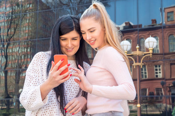 istock two smiling girls with phone 1143736672