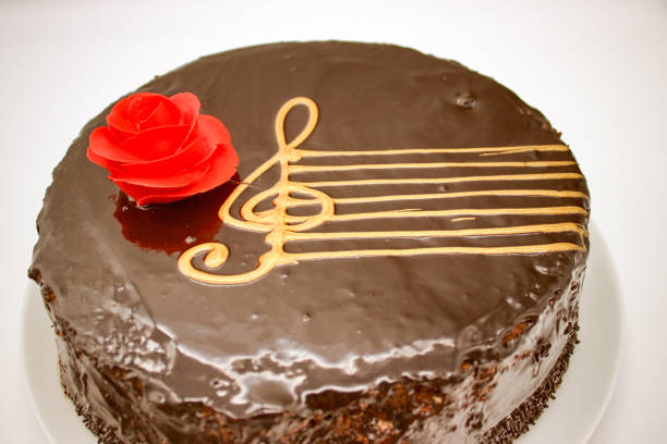 istock Chocolate cake on a white background. Image from above. The cake is decorated with a red flower of cream and a stylized musical style with a G-Clef 1143737615