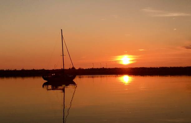 istock Sail boat with orange sunrise behind it 1143740229