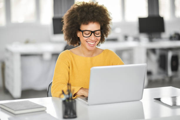 Smiling businesswoman using laptop in modern office. stock photo