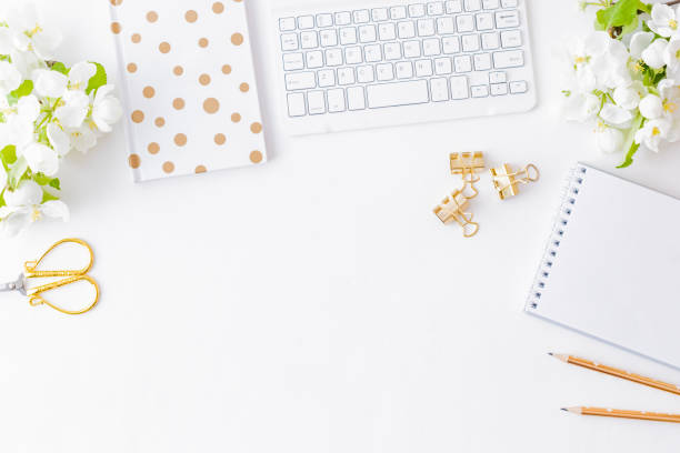 istock Flat lay blogger or freelancer workspace with a notebook, keyboard and white spring flowers on a white table 1143744443