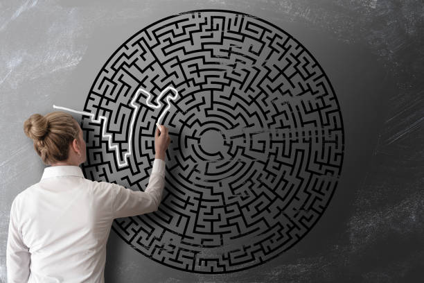woman trying to find way through chalk drawing of maze on blackboard challenge concept - maze solution business plan imagens e fotografias de stock