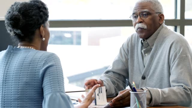 Senior African American man talks with bank manager