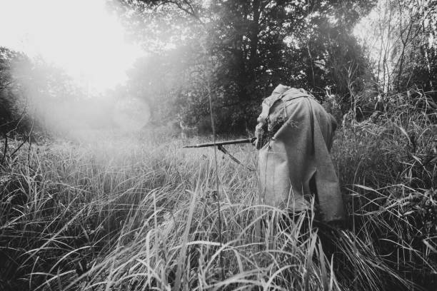 Re-enactor Dressed As World War II Russian Soviet Red Army Soldier Fast Running With Rifle Weapon Through Autumn Forest. Soldier Of WWII WW2 Times. Photo In Black And White Colors.