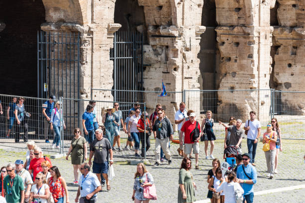 Rome, Italy - September 4, 2018: Many people tourists group exiting through exit gates from Colosseum amphitheater on sunny summer day on guided tour with guide