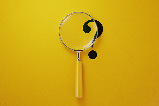 Magnifier and question mark on yellow background. Horizontal composition with copy space.