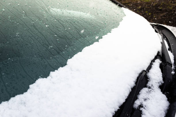 istock Car windshield and wiper under snow. Snowfall in city, changing weather. 1143754420