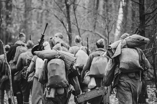 Re-enactors vestidos como soldados rusos del ejército rojo soviético de la II Guerra Mundial marchando a través del bosque en el día de otoño. Foto en colores blanco y negro. Soldado de la segunda guerra mundial WW2 Times photo