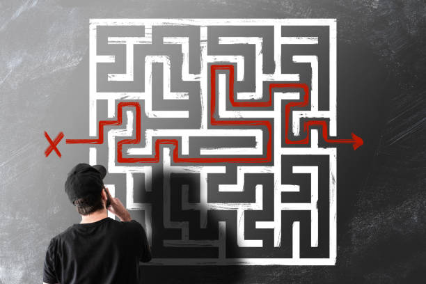 man looking at chalk drawing of maze labyrinth on blackboard