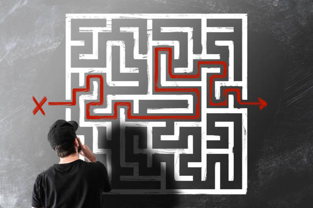man looking at chalk drawing of maze labyrinth on blackboard - maze solution business plan imagens e fotografias de stock