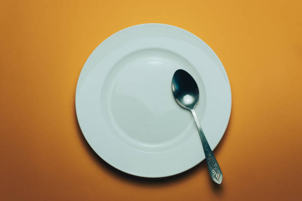 istock White bowl and a fork with a spoon on an orange background 1143760827