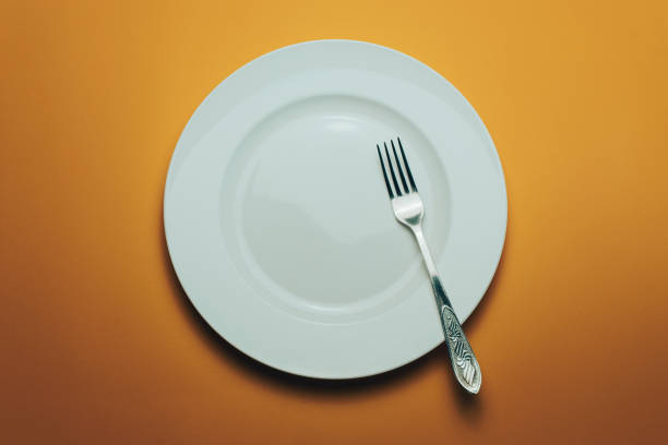 istock White bowl and a fork with a spoon on an orange background 1143761798