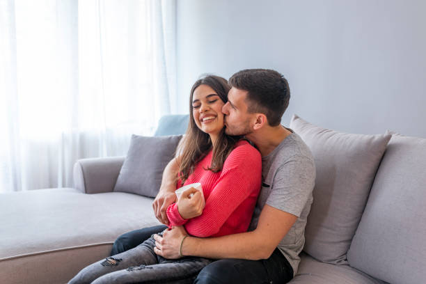 istock Beautiful young couple is talking and smiling while sitting on sofa at home 1143761938