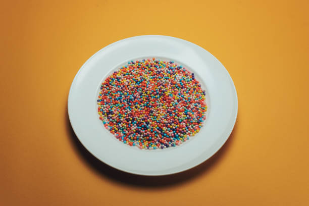 istock White plate with color preparations (vitamins, dyes, flavor enhancers, nutritional supplements, innovative technologies, candy sweets) on an orange background. 1143761942