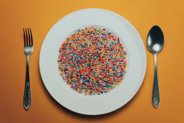 istock White plate with color preparations (vitamins, dyes, flavor enhancers, nutritional supplements, innovative technologies, candy sweets) on an orange background. 1143762050